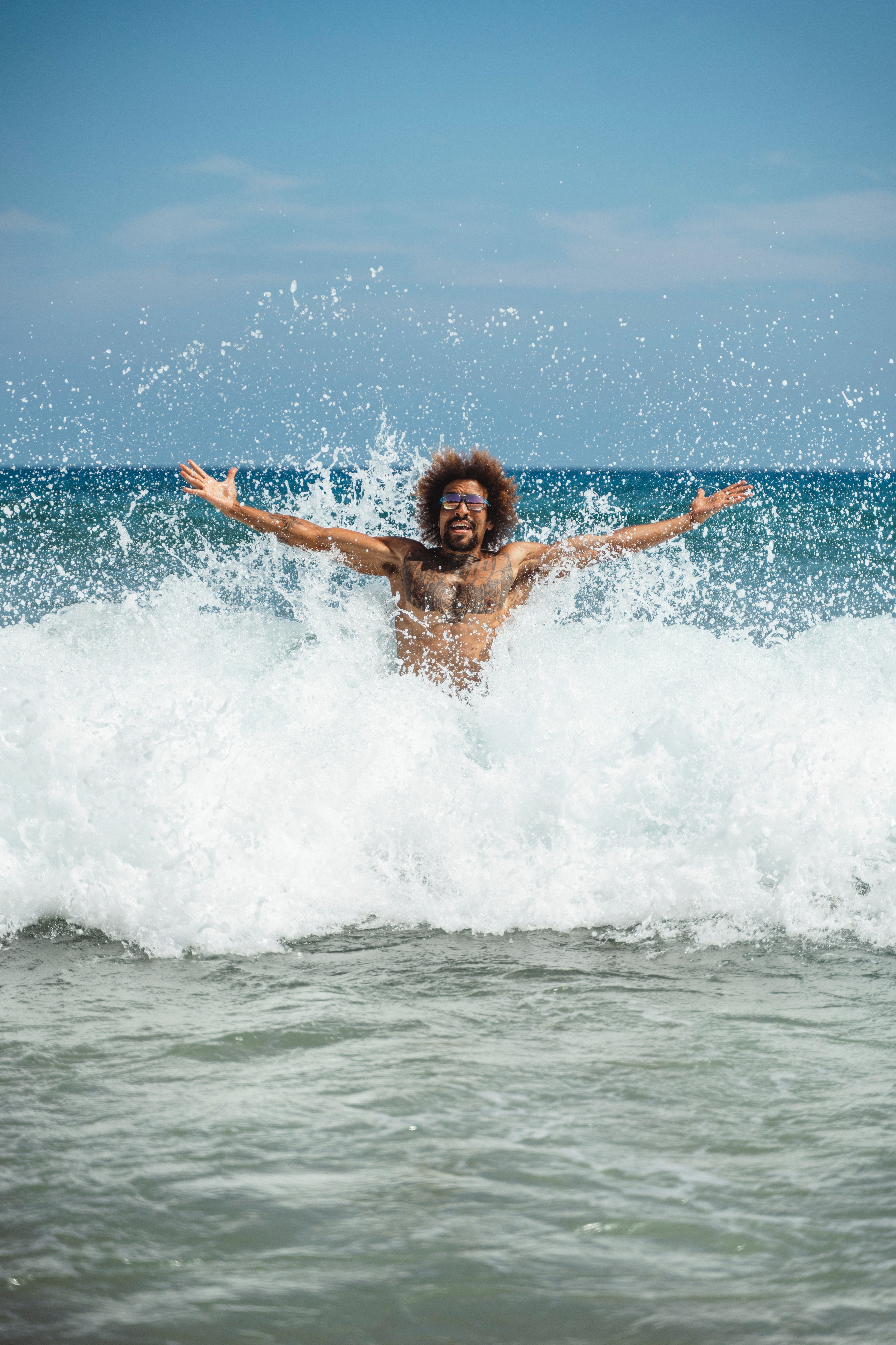 Man wearing Tifosi sunglasses in the ocean breaking a wave