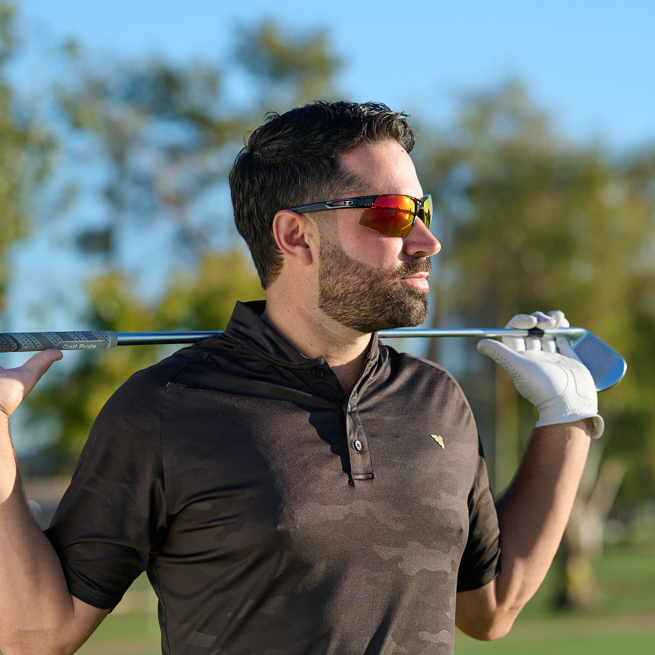Man on golf course holding club behind neck