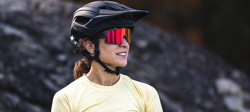Female looking to side wearing bike helmet and red shield sunglasses