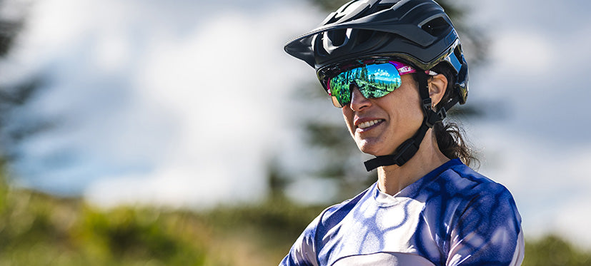 Woman cyclist smiling wearing a helmet and shield sunglasses