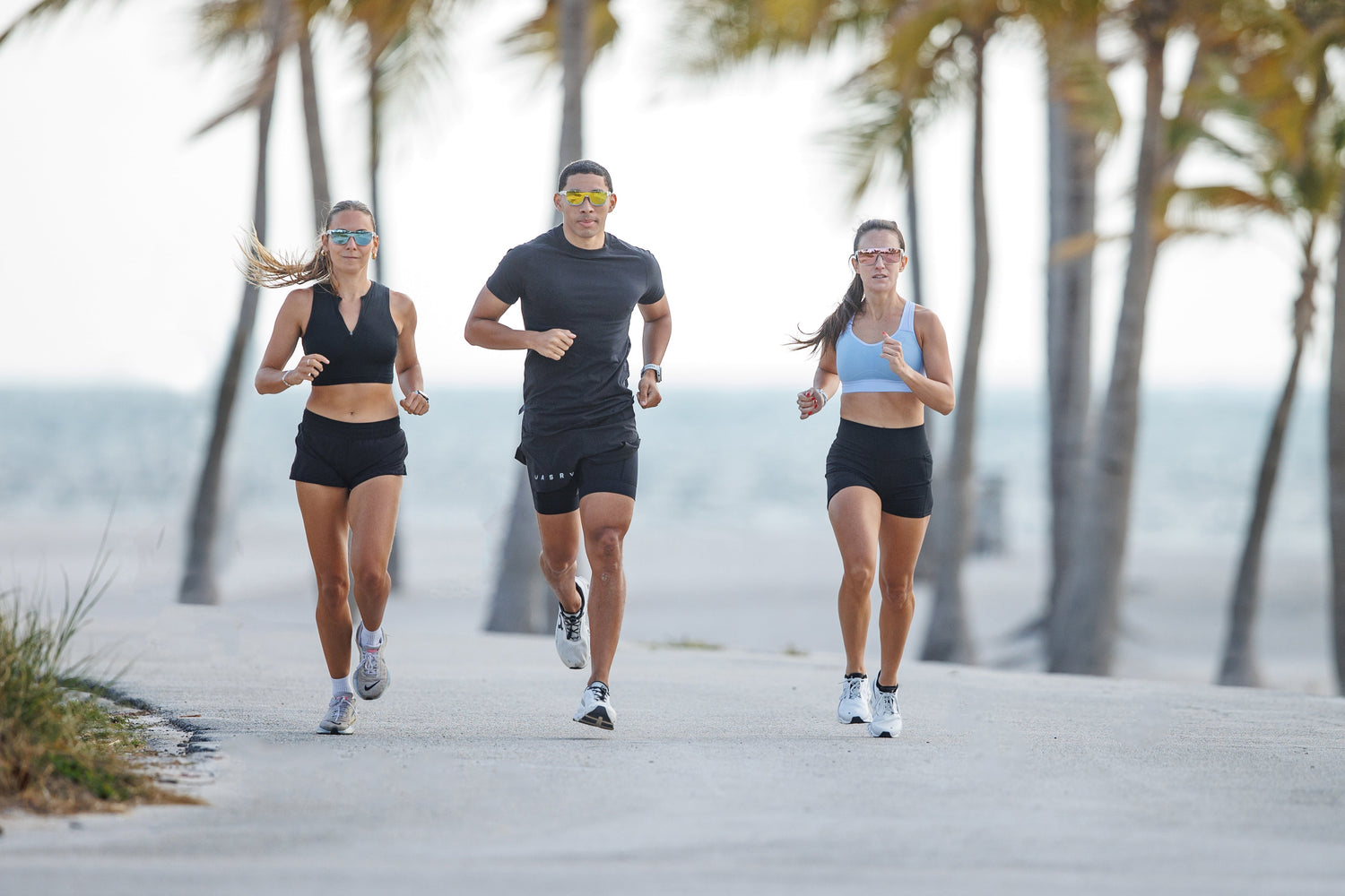 3 people running in Tifosi sunglasses on a road by the beach