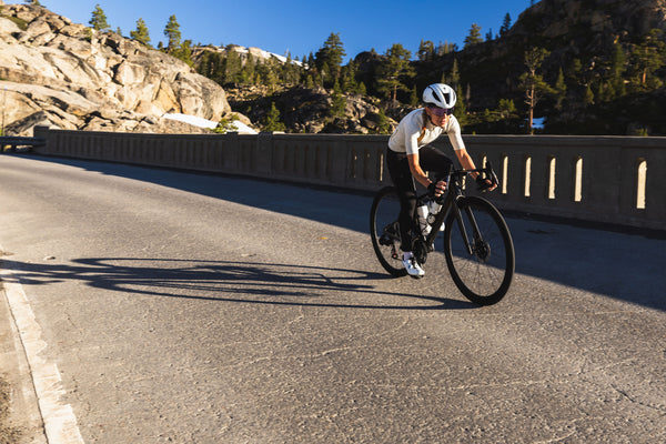 Cyclist riding on a mountain road with rocky cliffs and trees in the background