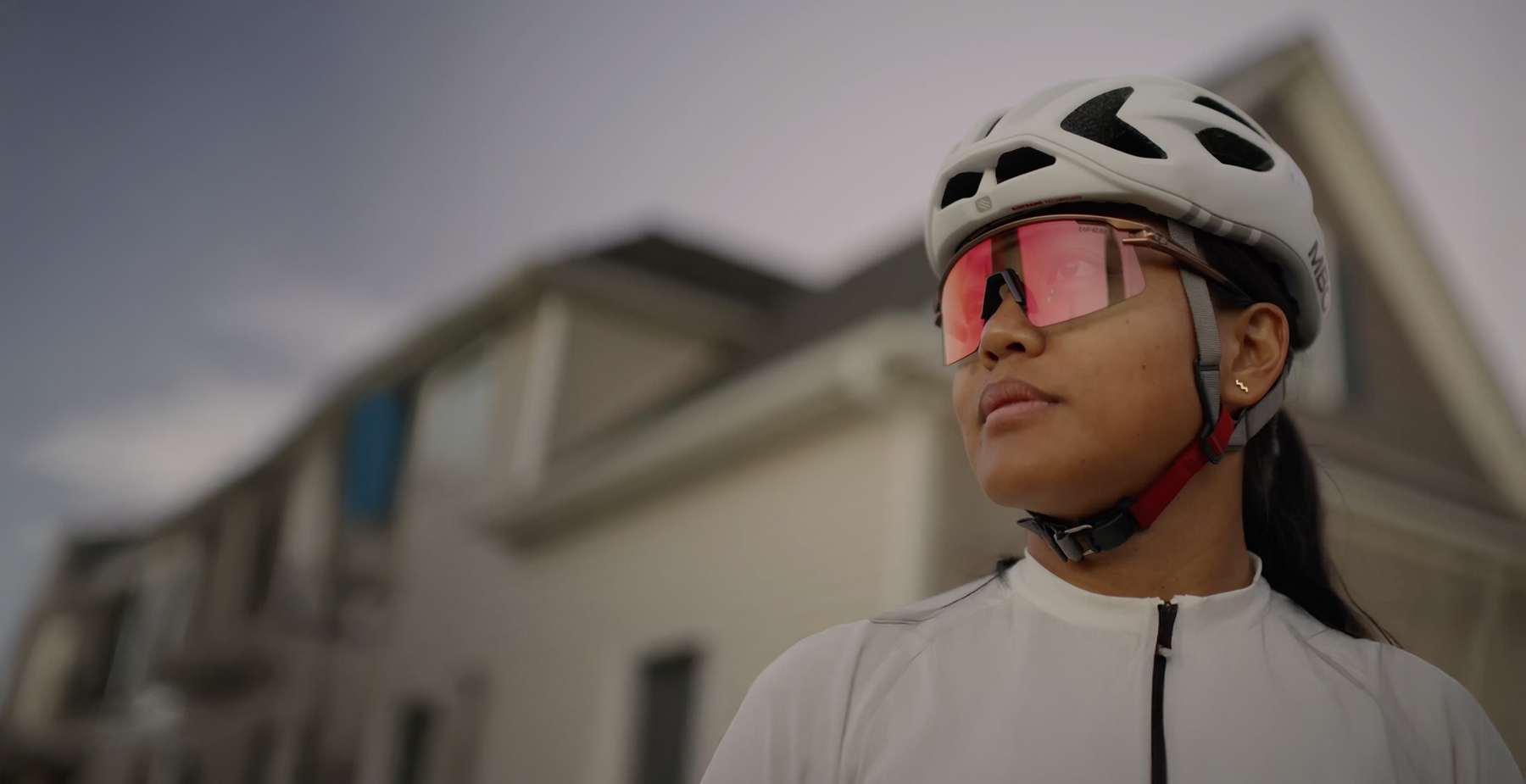 Person wearing a helmet and reflective glasses with a blurred building in the background