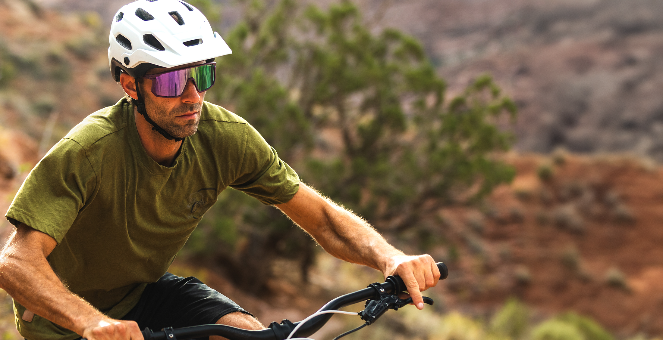 Man riding a bike on a trail with a helmet and sunglasses